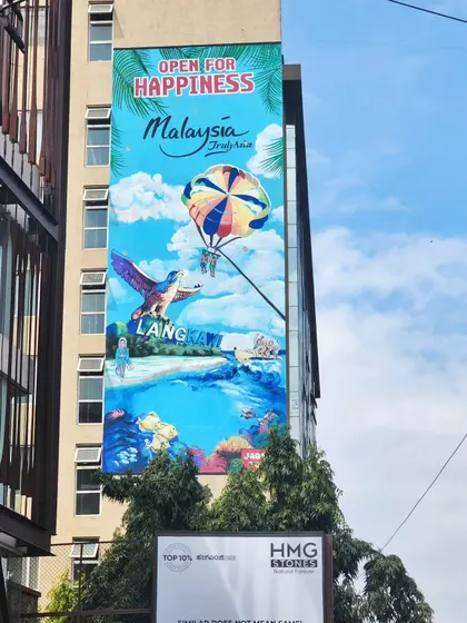 A clear, straight-on shot of the Langkawi mural, with its bright blue sky and parasailing adventure.