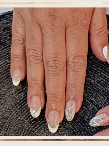 A beautiful bridal or party look. This set features a classic white French tip with some nails accented by a silver glitter ombré and delicate white line art.