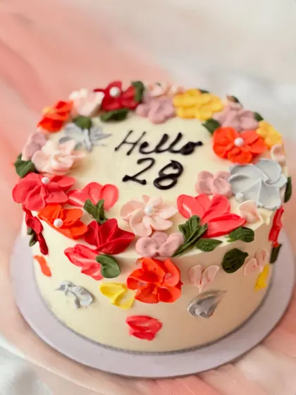 A vibrant birthday cake decorated with colorful palette knife buttercream flowers. The abstract, textured floral design gives it a modern and artistic feel.