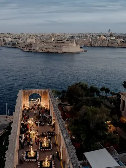 A breathtaking drone shot of the sundowner mehendi venue in Malta, perched on the edge of the sea, showcasing the epic scale of the event.