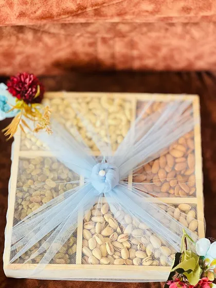 A slightly angled view of the dry fruit box, highlighting the texture of the nuts and the delicate net wrapping.