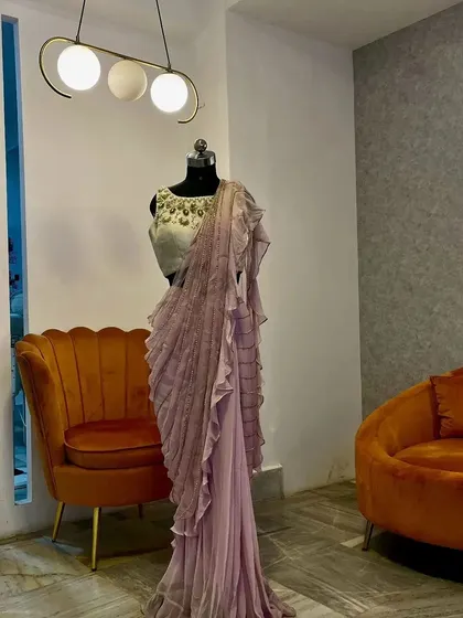 The lavender ruffle saree displayed on a mannequin, giving a clear view of the full outfit, including the embellished blouse and the tiered ruffles.