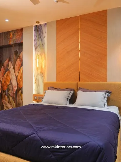 A bedroom in the Tata Tritvam apartment, where the headboard is flanked by artistic, back-lit panels and complemented by a custom wardrobe.