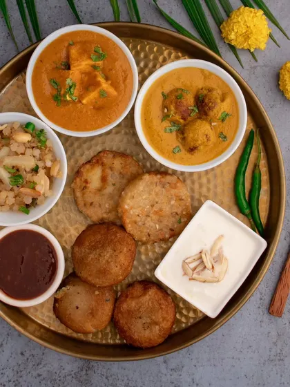 A beautiful 'Upvas Thali' shot for Shivratri. This platter, featuring sabudana vada, paneer, and other fasting foods, is styled to look like a feast, making fasting feel like a celebration.