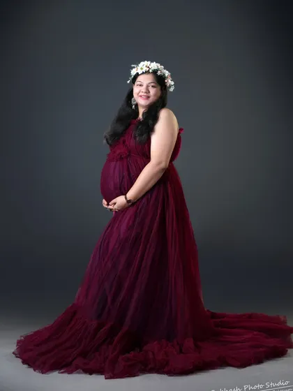 A classic studio maternity portrait in our wine-colored tulle gown. The floral crown adds a touch of softness to the elegant look.
