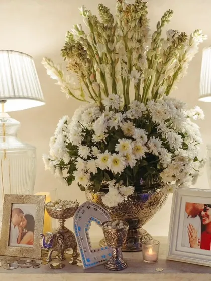 A beautiful decor setup for the Sufi Night, with large arrangements of white tuberoses and chrysanthemums, framed photos of the couple, and soft candlelight.