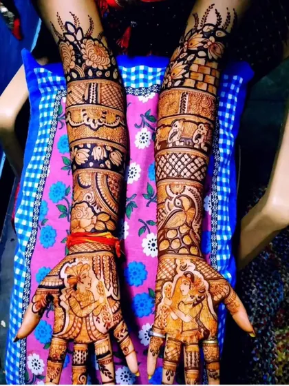 A beautiful example of a story mehendi with portraits. The design includes the couple on the palms, with peacocks, elephants, and floral bands on the arms.