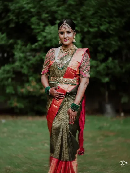 A full-length portrait of the bride in her stunning green and red saree, looking regal and elegant.