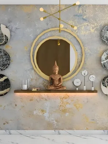 An artistic and eclectic foyer wall featuring a central Buddha statue on a backlit shelf. The composition is balanced by a modern gold mirror and a collection of decorative plates with abstract map designs, creating a unique and personalized entry.