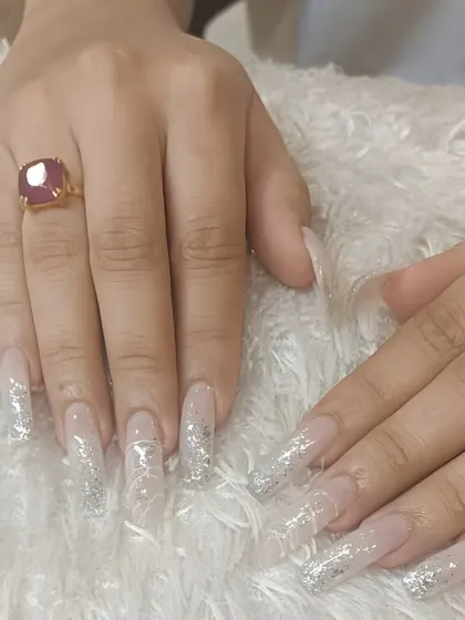 Extra-long coffin extensions with a clear base and sparkling silver glitter accents. This is a dramatic and glamorous look for those who want to make a statement.