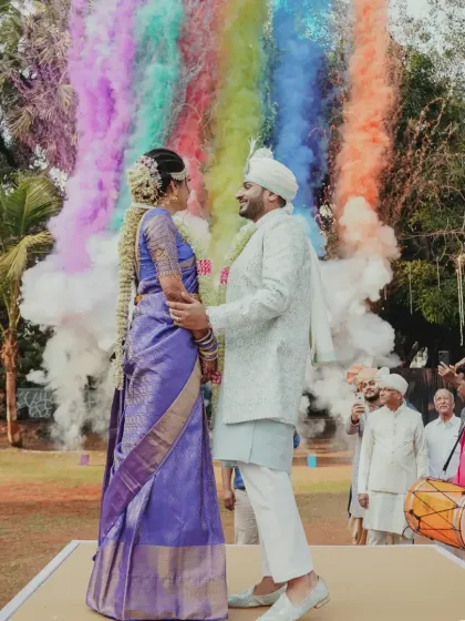 A vibrant Varmala moment, made even more spectacular with a burst of rainbow-colored smoke, creating a joyful and unforgettable photo opportunity for the couple.