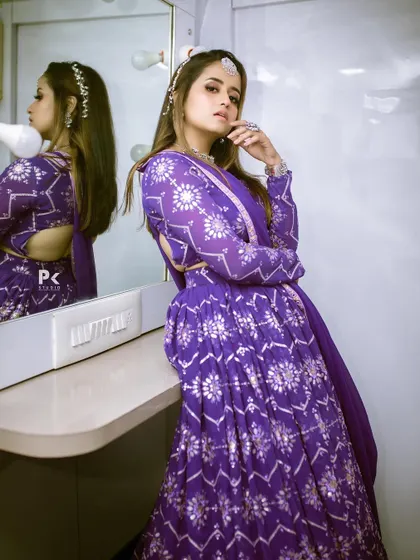 A stylish pose showing the side profile and backless design of the purple lehenga's blouse.