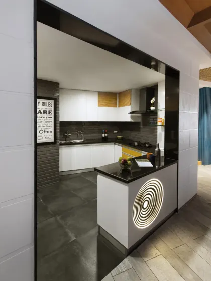 The modern open kitchen in the Grey Apartment features a graphic backlit counter and pops of yellow. It is both a practical workspace and a visual highlight, connecting seamlessly to the dining area.