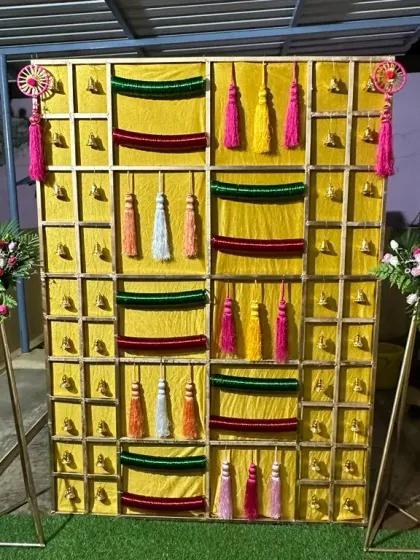 Another view of the yellow tassel backdrop, flanked by modern floral stands.