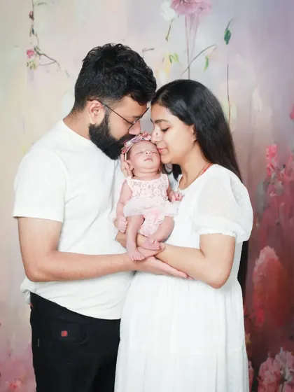The most cherished moments. This new family of three is surrounded by love in this beautiful portrait against a soft, floral backdrop.