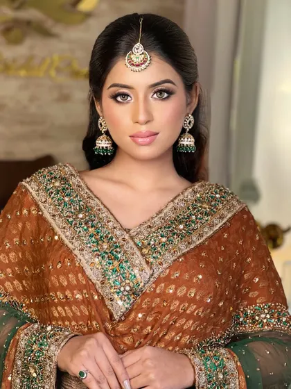 A classic bridal portrait from one of our masterclasses. This look features soft brown and gold eyeshadow, defined brows, and a neutral lip color, perfectly complementing the traditional brown and green bridal attire.