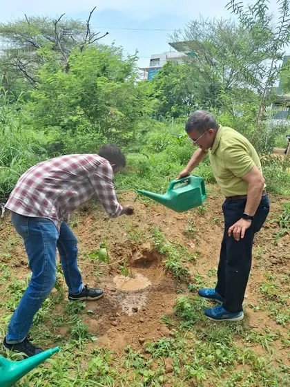 An Infoglen team member waters a freshly planted sapling, a simple but crucial step in ensuring its survival and growth.