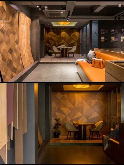 The showroom features multiple zones, including this cozy discussion nook set against a backdrop of geometric wood paneling. The design creates a variety of experiences within one open-plan space.