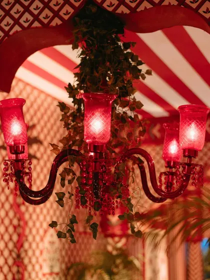 A close-up of a red glass chandelier hanging in a space with red and white patterned walls and ceilings, creating a vibrant, cohesive look.