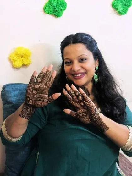 A smiling client showing off her freshly done mehendi. The design is a classic Indian pattern, suitable for any festive occasion.