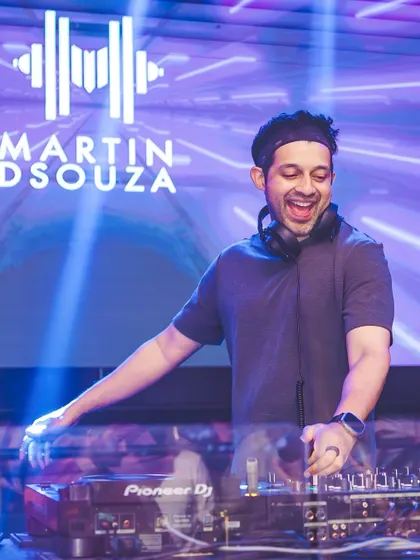 A smiling shot of me behind the decks with my logo on the screen behind.