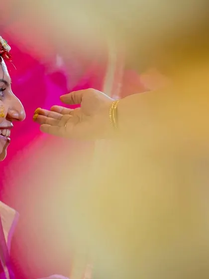 A tender moment during the haldi, as a family member gently applies turmeric to the bride's face.