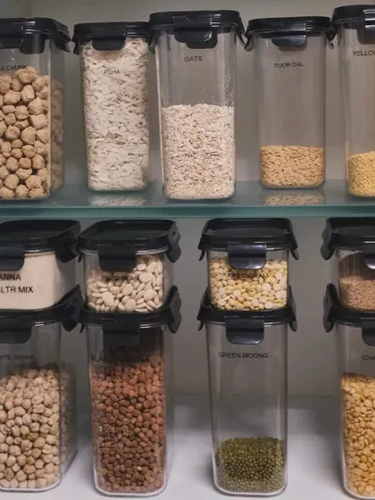 Stacking clear containers is a great way to use vertical space inside a cabinet. This setup for dals and health mixes is both space-efficient and easy to navigate.