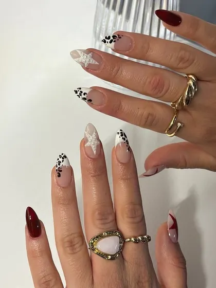 A cool, edgy set with a mix of deep red, leopard print, and a glittery star accent nail.