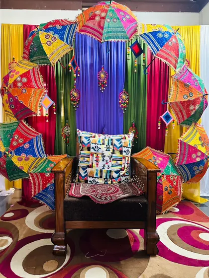 To bring a festive and colorful Rajasthani vibe to an event, I created this unique photo corner. An arch of vibrant, embroidered umbrellas provides a joyful and memorable backdrop for any celebration.
