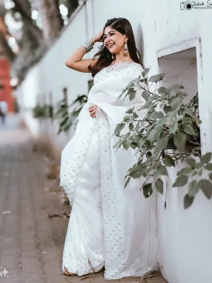 A full-length shot showing the actress leaning against a wall, creating a relaxed and candid feel.