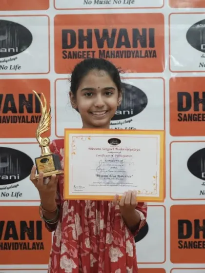 A young student proudly holds her certificate and trophy.