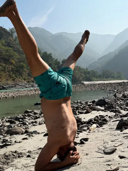 A participant practicing a headstand on the sandy banks of the Ganga. Taking our practice outdoors challenges our balance and deepens our connection to the elements.