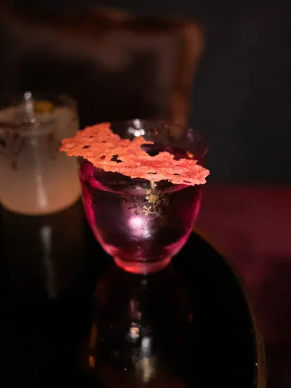 A moody, atmospheric shot of a pink cocktail in a dark setting. This image focuses on creating a vibe, perfect for a sophisticated bar or lounge.