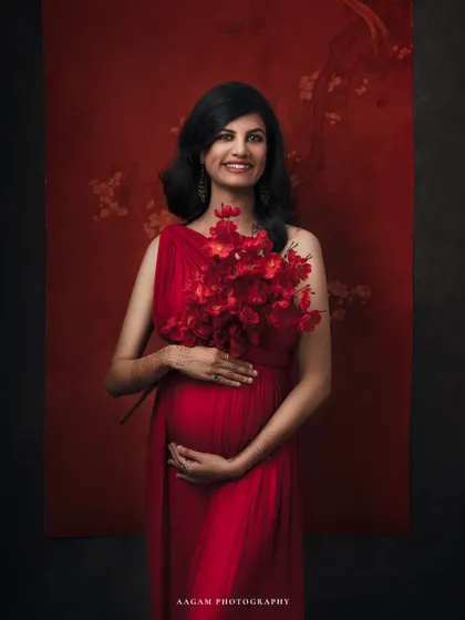 Holding a bouquet of matching red florals, this portrait adds a touch of softness to the bold color, celebrating the life blooming within.