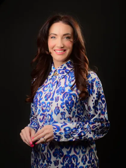 A vibrant professional portrait for a female executive. The colorful blouse and confident smile create a memorable and energetic headshot.