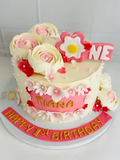 A beautiful first birthday cake adorned with delicate, handcrafted sugar flowers.