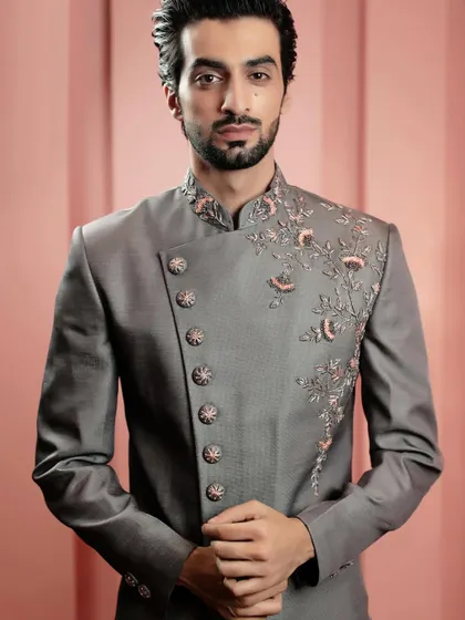This grey bandhgala features an asymmetrical cut and subtle floral embroidery, mixing traditional elements with a modern design sensibility for a truly unique look.