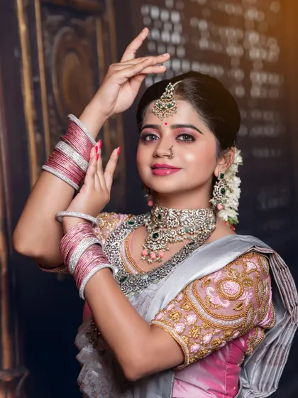 A graceful pose in a silver tissue saree, this shot highlights the pink bangles and the detailed embroidery on the blouse.