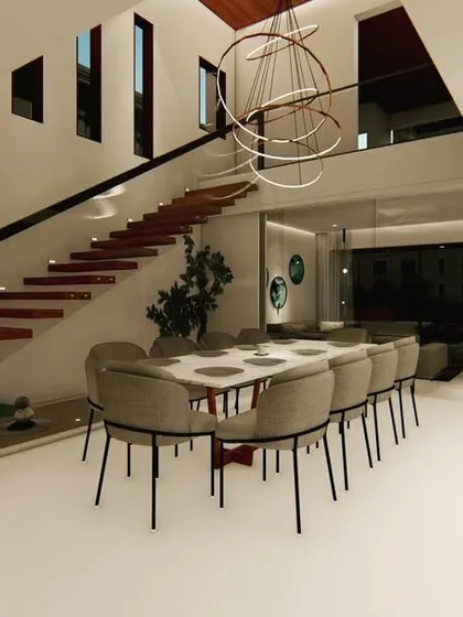 This dining area is set below a floating staircase and a dramatic modern chandelier. The open design connects it to the living room and upper floor, making it a central hub for family gatherings.