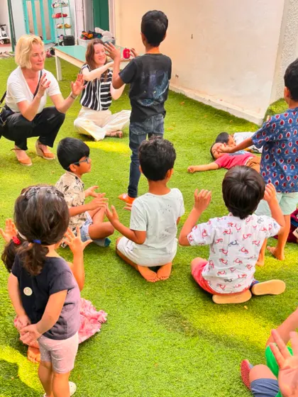 The Ambassador joins the children in a circle game on the grass. Play is a universal language that bridges all ages and cultures.