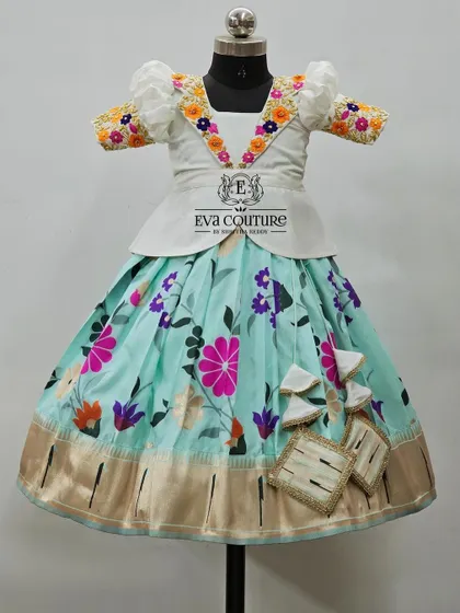 A white peplum blouse with colorful floral embroidery on the collar, paired with a pastel blue floral skirt.