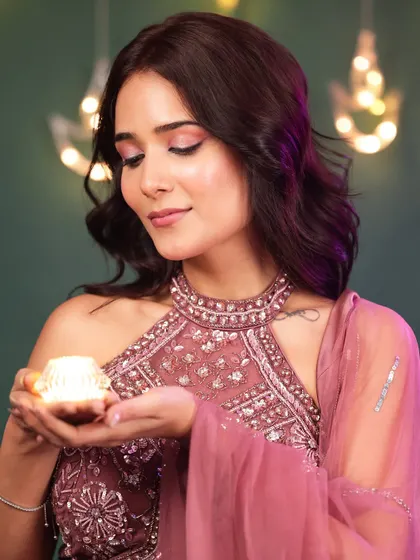 A soft and gentle Diwali portrait. The model holds a diya with a serene expression, and the fairy lights in the background add a magical, festive bokeh effect.