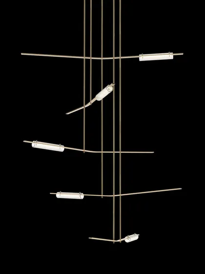 The Volant chandelier by Gabriel Scott, shown against a black background to emphasize its pure, architectural form. The angled, tubular glass elements give the impression of objects in orbit.