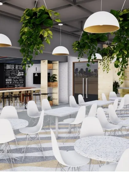 The canteen features varied seating arrangements, from bar-style counters to small group tables. Lush hanging greenery and modern pendant lights create a fresh and inviting atmosphere for relaxation and socializing.