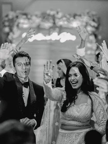 The energy is electric as the couple makes their grand entrance, cheered on by their closest friends. This black and white shot freezes a moment of pure, unadulterated joy and celebration, showing the fun side of your big day.