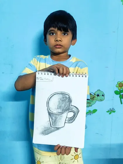 A proud student holding his completed pencil sketch of a mug. It's wonderful to see their confidence grow with each drawing.