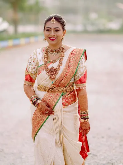 Deekshitha looking radiant on her wedding day. The custom blouse with its traditional design and puff sleeves completes her classic South Indian bridal look.