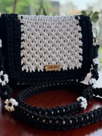 My classic black and white sling bag. The strap is decorated with delicate white macrame flowers, making it a truly unique piece.
