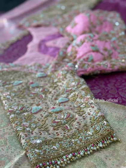 A close-up of the intricate embroidery on the pink blouse.