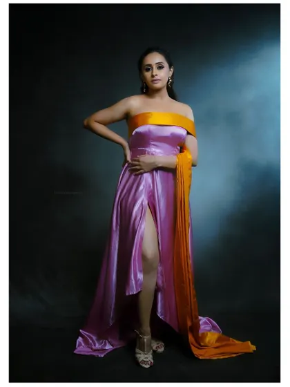 A full-length portrait in a dramatic pink and orange gown. The studio lighting is used to create a regal and powerful image.
